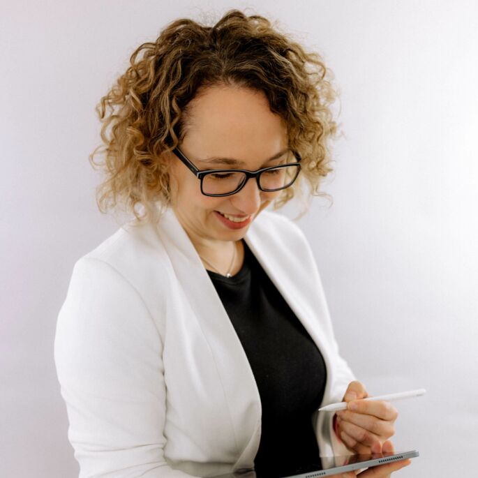 Webentwicklerin Nicole Weiß blickt auf ihr Tablet, digitaler Stift in der Hand, vorbereitet auf die Planung Ihres Webprojekts.